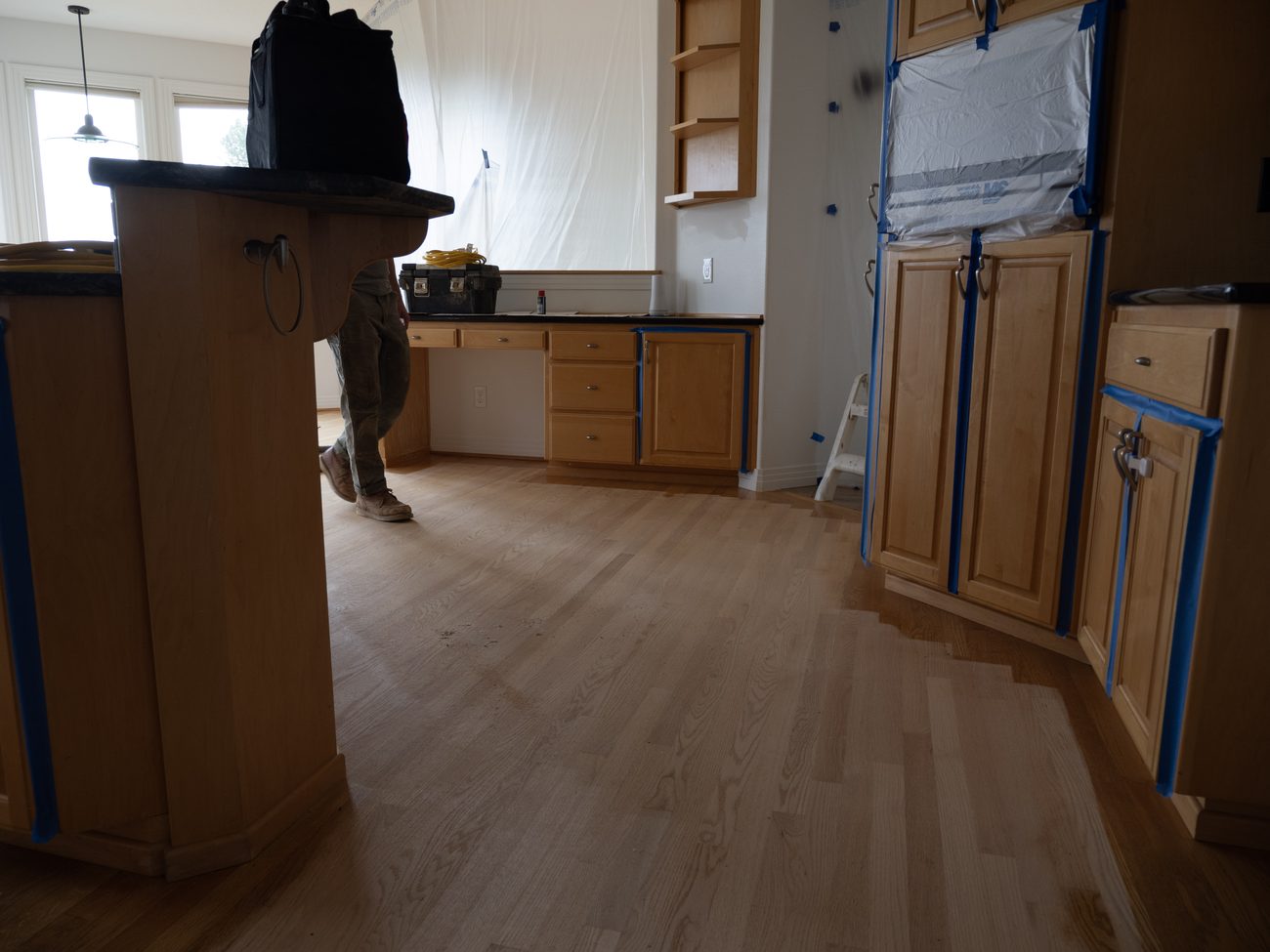 Red oak floor refinish with the work area sealed off for dust containment