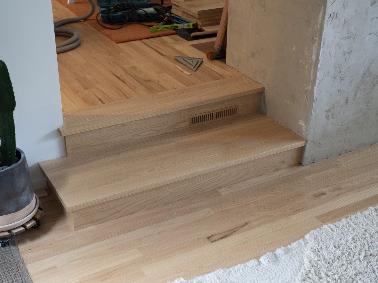 Custom red oak stair tread with a custom matched floor vent